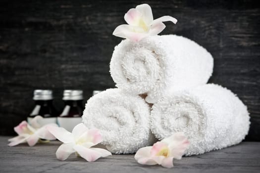 White rolled up towels with body care products at spa