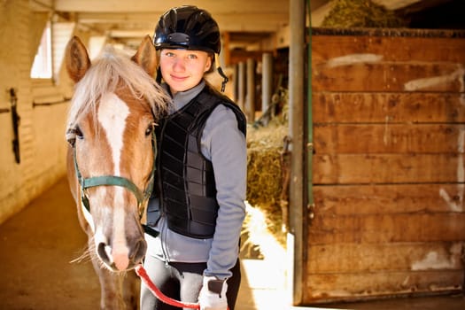 Portrait of teenage girl with horse in stable