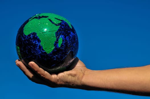 Vintage Old Globe Earth and Human Hand over a Blue Sky
