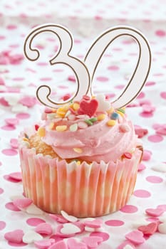 Small colorful cupcake with pink sprinkles for the 30th birthday