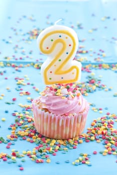 Small colorful cupcake with pink sprinkles for second birthday