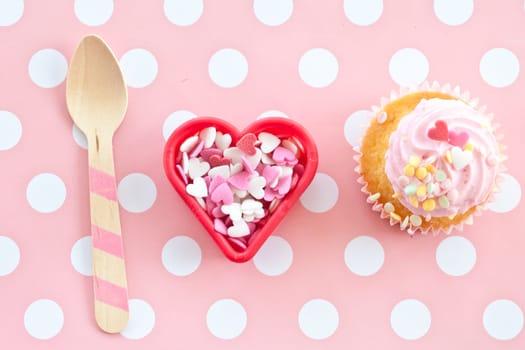 Small colorful cupcake with pink sprinkles in heart shape
