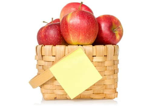 Red apples in woven basket with sticky note. Isolated on the white background