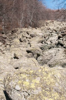 Old moraine rocks with moss in winter sunny day landscape