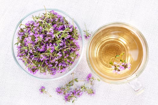 Bowl of fresh thyme sprigs with herbal tea in cup from above