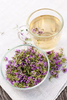 Bowl of fresh thyme sprigs with herbal tea in cup from above