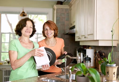 Mother and daughter doing dishes in kitchen at home
