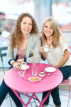 Two smiling women meeting for coffee in cafe