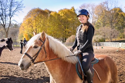 Portrait of teenage girl riding horse outdoors on sunny autumn day
