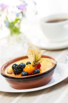 Sweet creme brulee dessert topped with fresh berries and coffee