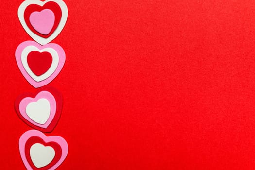 Border of romantic red pink and white hearts for Valentines day on crimson background