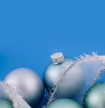 Glass Christmas balls with holiday ribbon on blue background