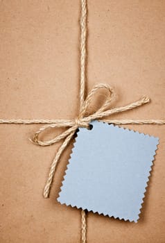 Gift package and blue tag in brown paper wrapper tied with string close up