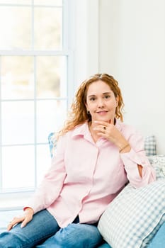 Smiling caucasian woman relaxing on couch by window