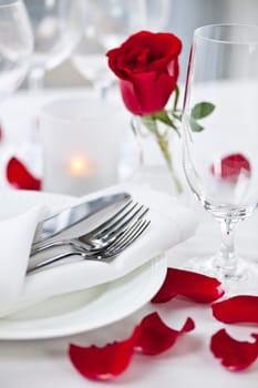 Romantic table setting with rose petals plates and cutlery