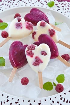 Ice cream on the stem in heart shape with fresh raspberries