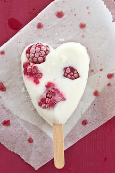 Ice cream on the stem in heart shape with fresh raspberries