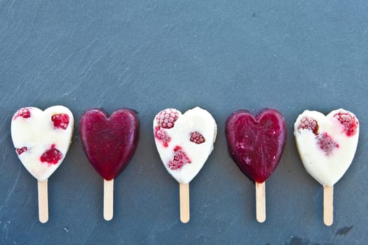 Ice cream on the stem in heart shape with fresh raspberries