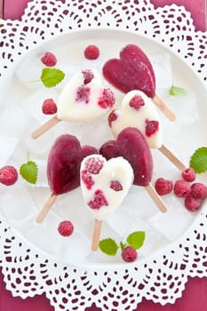 Ice cream on the stem in heart shape with fresh raspberries