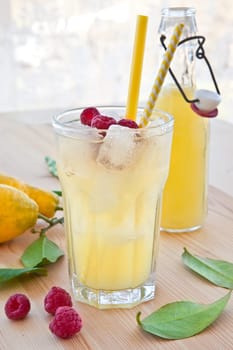 Cold lemonade with fresh lemons and raspberries