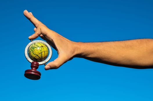 Vintage Old Globe Earth and Human Hand over a Blue Sky