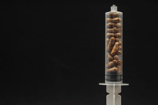 Medical Syringe Full of Pill Drugs on a Black Background