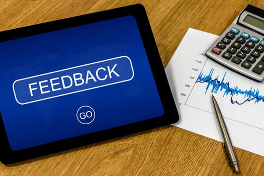 feedback word on digital tablet with calculator and financial graph