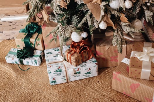 Wrapped in golden paper present boxes on table closeup and veautiful holdiay decorated christmas tree with ornaments and garland unfocused. Winter holiday background