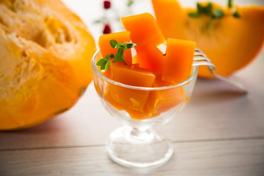 Prepared sweet pumpkin marmalade in a glass bowl on a wooden table. Autumn recipes.
