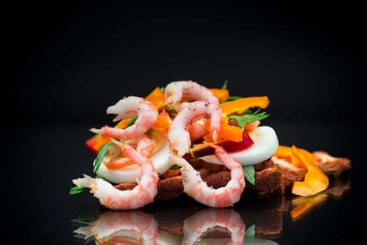 cooked sandwich with shrimp, eggs, pepper and greens, isolated on black background