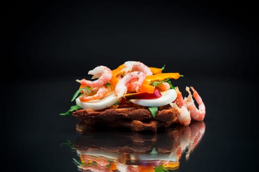 cooked sandwich with shrimp, eggs, pepper and greens, isolated on black background