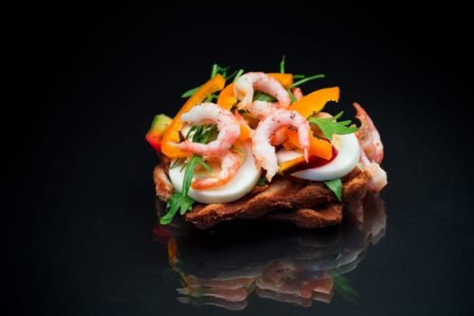 cooked sandwich with shrimp, eggs, pepper and greens, isolated on black background
