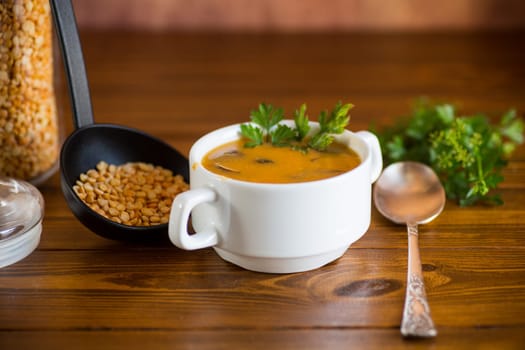 Cooked dried pea puree soup with mushrooms in a bowl on a dark wooden table.