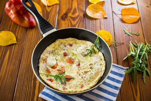 Fried omelets with various autumn vegetables in a frying pan on a wooden table. Autumn recipes.