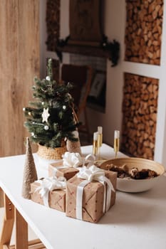 Wrapped in golden paper present boxes on table closeup and veautiful holdiay decorated christmas tree with ornaments and garland unfocused. Winter holiday background