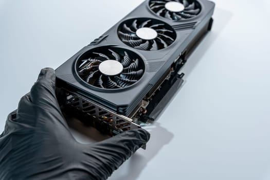 the hand of a computer technician holds a modern powerful video game card for a computer with three fans. the concept of PC hardware. Gaming video card