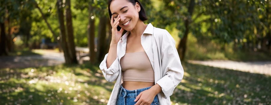 Stylish asian girl walks in park, laughs and enjoys summer weather. People and lifestyle concept.