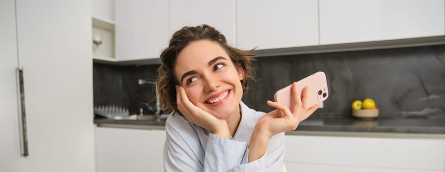 Portrait of woman thinking while holding smartphone, deciding what to order on mobile phone app.