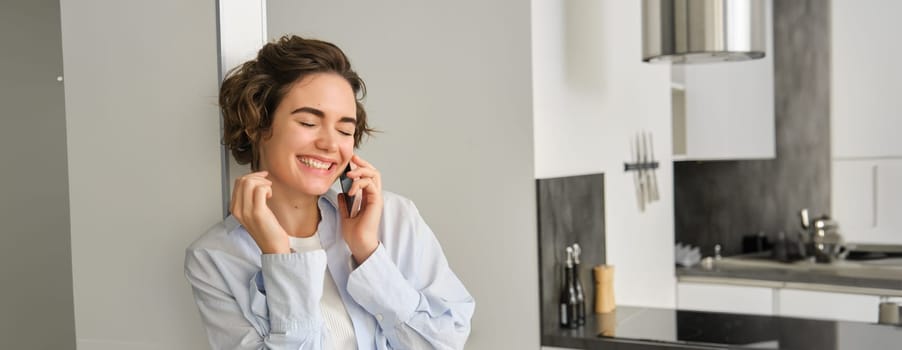 Image of happy woman talking on mobile phone, having a chat, using smartphone, laughing and smiling, calling from home.