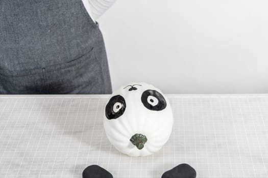 Painting panda face with black acrylic paint to make panda pumpkin for Halloween.