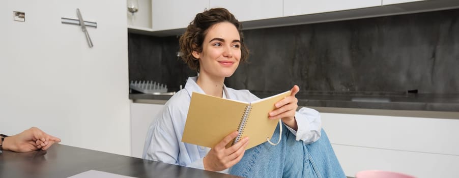 Portrait of businesswoman at home, wrtiting in journal, making plans in her planner, spending time indoors.