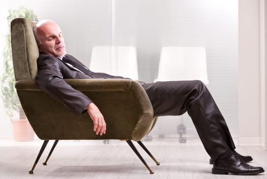 mature businessman asleep on a green retro armchair