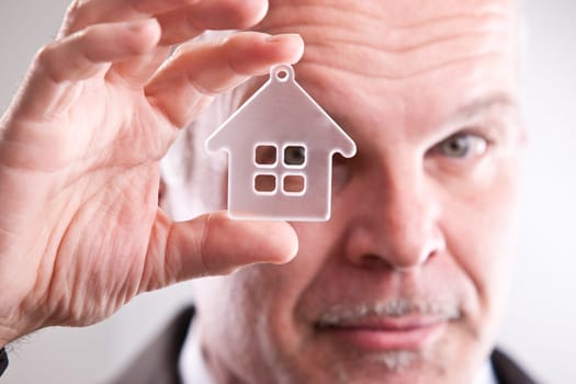 middle aged Man with looking through a little house in his hand