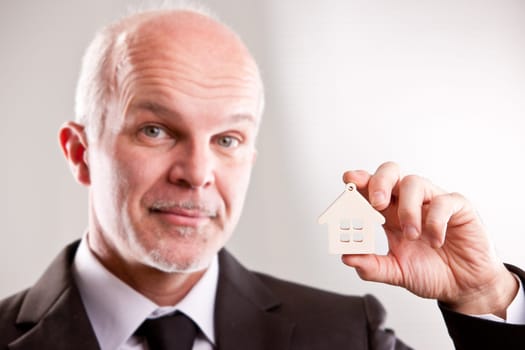 middle aged Man with a little house in his hand looking at you