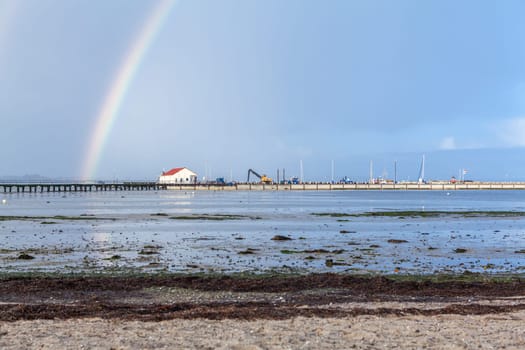 colorful rainbow at the sea at the baltic sea in front of blue sky in autumn landscape beauty