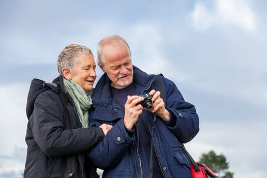 older adult couple seniors happy to take self-portrait photograph with digital camera on vacation