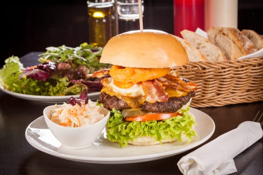 Delicious hamburger cheeseburger with bacon egg and salad on a plate