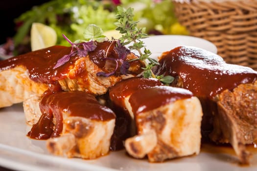 Grilled pork ribs Spareribs with barbecue sauce marinade and herb salad on a plate