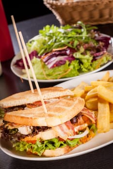 Club sandwich on toasted white bread with bacon and fries fried fries on a plate