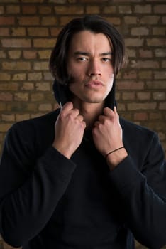 Portrait of handsome Malaysian man wearing hoodie and looking serious